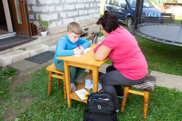 Outdoor learning with a student and tutor, working together at a table, in a backyard setting, showing the comforts of home-based education.