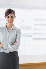 Businesswoman wearing suit standing by table in office presenting before blurred screen, copy space