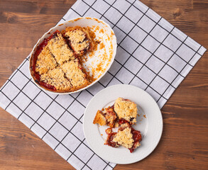 Overhead View of Homemade Plum Crumble Pie Served on Plate. Rustic Fruit Dessert with Golden Topping on Checkered Cloth
