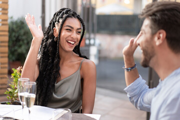 Happy woman laughing, her hand raised in anticipation of a high five with a friend at a celebration.
