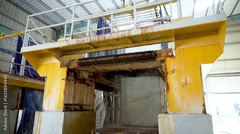 Poster large marble cutting machine slicing marble blocks in a factory. water cools the blade during marble