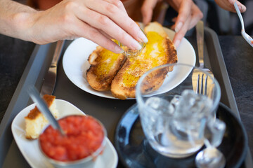 Woman pouring olive oil on toasted bread for breakfast