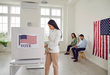 Vote. Woman voter participates in democratic process in voting booth during American election. Responsible citizen at polling station stands in front of voting booth preparing to cast her vote.