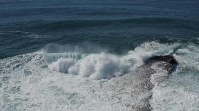 A large ocean wave curls and breaks over an exposed reef. Captured from high above during a storm swell on the East Coast of Australia.