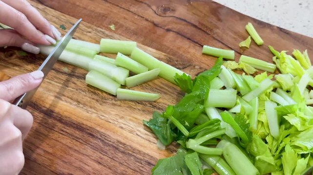 Slicing Fresh Celery Stalks on Wooden Cutting Board