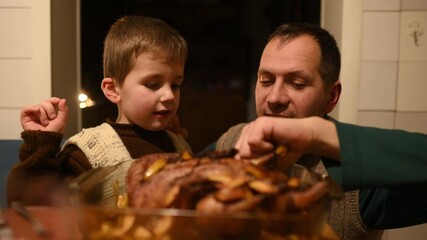 Family celebrates Christmas or Thanksgiving. son and father tastes tasty morsels of roasted turkey duck. family traditions celebrating holidays together