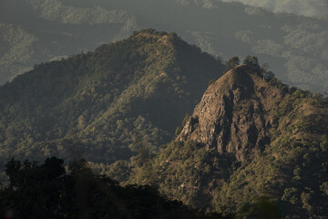 Misty Mountain Ridge with Sunlit Forest at the Summit. Layered green mountains with dramatic...