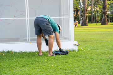A person bends down to organize painting tools on grass in front of an art installation.