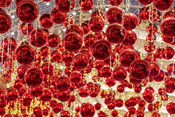 Hanging red Christmas baubles with golden string lights in a festive indoor setting.