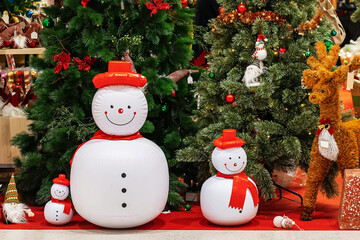 Indoor Christmas decoration with inflatable snowmen, Christmas trees, and festive ornaments.