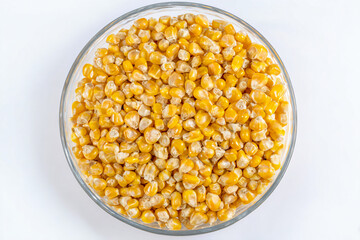 a bowl of corn kernels on a white surface