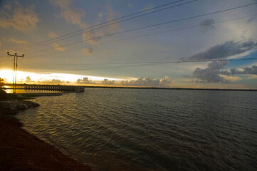 Tranquil Sunset Over Lakeside with Pier and Power Lines