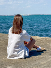 A serene moment by the water: a young woman with brown hair enjoys tranquility by the sea on a...