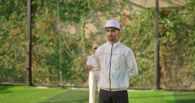 Indian young adult gen z bowler woman standing outdoor match play ground wear uniform cap asian female lady throwing ball do practice clap hand umpire man show a gesture of six with two hands signal