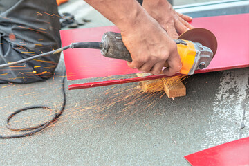 Cutting roof tile for roof repairing. Precision metal cutting in progress. Sparks fly as a metal sheet is sectioned