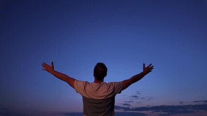 Man with arms wide open enjoying outdoors during blue hour time in nature.