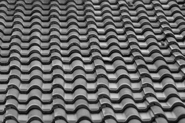 This is a black - and - white image of a roof covered with interlocking, wave - shaped tiles. The tiles create a repetitive, undulating pattern