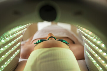 Woman receiving green LED phototherapy inside dome close-up concept
