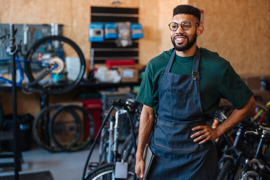 Bicycle mechanic smiling and holding tablet in repair shop