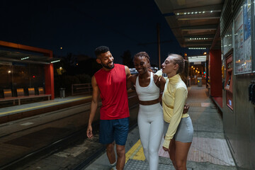 Fitness Friends Walking and Talking at Night at Tram Station