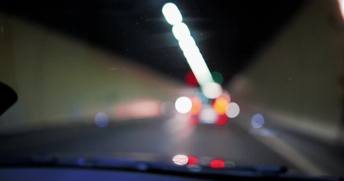 Blurred car lights oncoming traffic driving through dark tunnel. Wide angle view, bokeh headlights, real time, no people