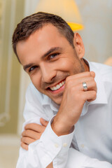 Happy groom with wedding ring smiling at camera