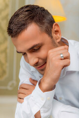 Thoughtful groom in white shirt showing wedding ring