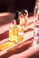 A sleek cosmetic serum bottle sits elegantly on a pink surface, bathed in sunlight. A close-up shot...