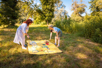 Active middle aged mother and young daughter playing badminton in the park. Concept of fitness,...