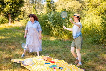 Caucasian family of two playing badminton with rackets in the park. Mother and daughter enjoying...