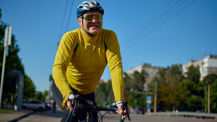Emotional cyclist pushing bike on city road under bright blue sky. Concept of fitness perseverance,...