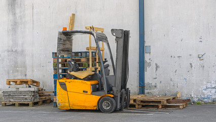 Used Yellow Electric Forklift in Front of Warehouse Building