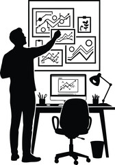 Silhouette of a man analyzing charts on a board next to a desk with a computer and lamp in black and white