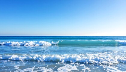 Fototapeta premium Calm ocean waves lapping a sandy shore under a vibrant blue sky