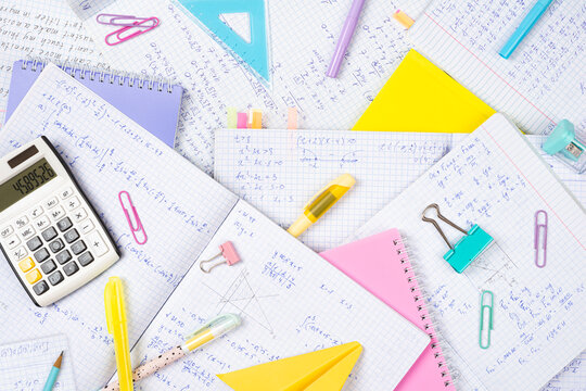 Background of many student exercise books white sheets with written mathematical formulas and colorful stationery objects