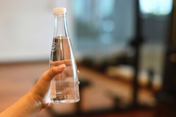 Elegant Glass Water Bottle Held in Hand Soft Lighting Clean Hydration Concept.