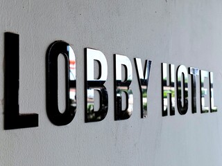 Hotel Lobby Sign Reflective Letters on Textured Wall Modern Architecture Detail.
