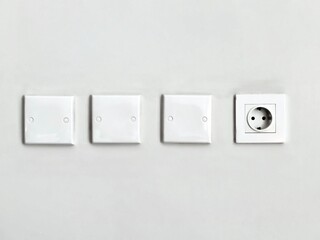 Minimalist White Wall with Three Blank Covers and One Electrical Outlet.