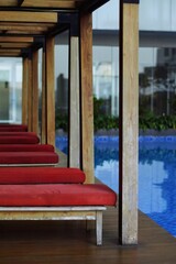 Serene Poolside Loungers Red Cushions and Wooden Pergola Structure.