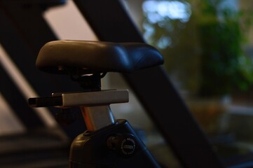 Stationary Bike Seat CloseUp Fitness Equipment Detail with Adjustments and Blurred Background.