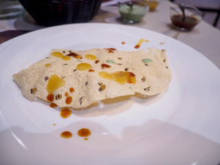 Crispy papadum seasoned with cumin, garnished with vibrant chutneys on white plate in restaurant dining scene