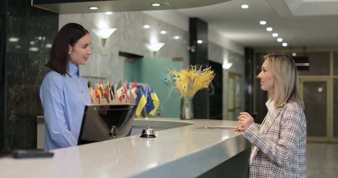 Woman check in at reception, entering hotel and gets key card at front desk. Hotel concierge worker welcoming tourist at resort.