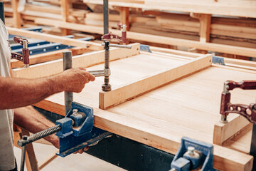 Woodworker Clamping Wooden Panel for Gluing and Assembly
