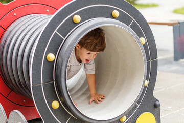 Excited boy crawling through playground tunnel