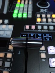 Close-up of a professional video switcher control panel with illuminated buttons and a transition fader lever.