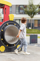 Little boy walking past playground tunnel