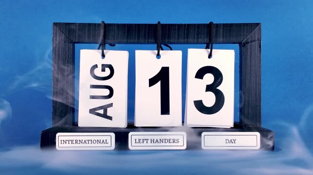 White smoke swirling around perpetual calendar displaying August 13 International Left Handers Day, highlighting recognition and pride for left handed community against vibrant blue studio backdrop