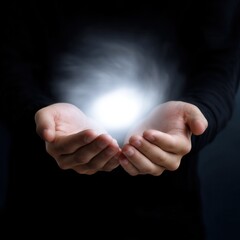 Mystical Hands Holding a Small Glowing Orb of White Light in Darkness
