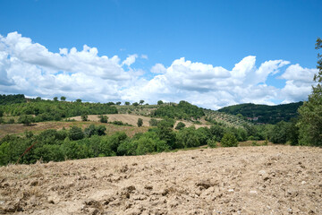 landscape of tuscany with blue sky with clouds and hills and trees
