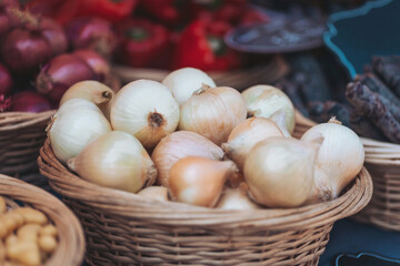 Fresh onions displayed in wicker baskets at a vibrant farmers market during the morning hours
